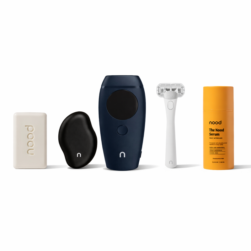 Nood Noodist Kit in navy blue including Buff Bar, black Eraser, Flasher 2.0 IPL device, razor, and Nood Serum daily aftercare on white background